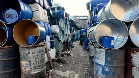 Empty barrels stacked high in muddy outdoor yard Vidéo 345156168