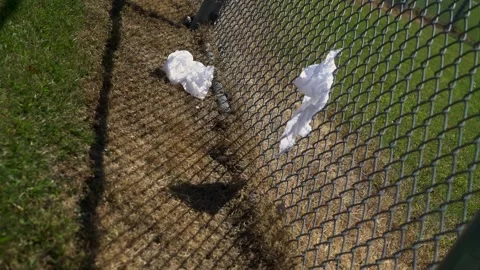 Empty baseball diamond with trash stuck to a fence on a hot summer day Vídeos de archivo 277404913