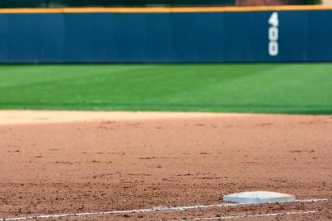 Empty baseball field highlights first base and outfield wall. Stock-Fotos