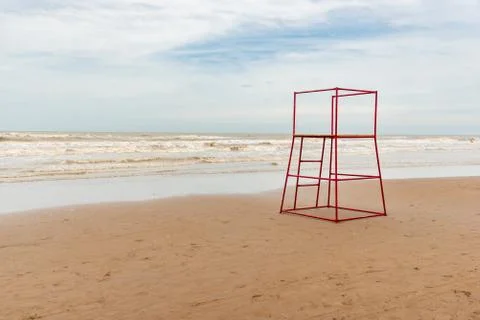 Empty beach in Argentina with high tide with a red lifeguard stand made of tu Stock Photos
