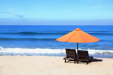 Empty beach background with bright tent, chairs, surf waves and sunny sky Stock Photos