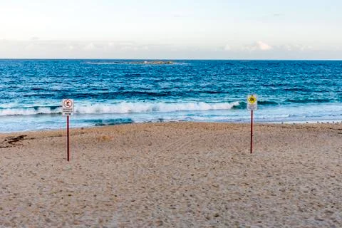 Empty beach, calm blue Pacific Ocean, signposts, sunny day. Stock Photos