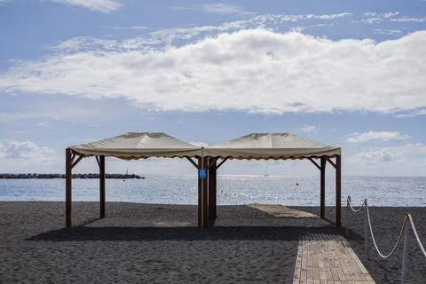 Empty beach canopy and boardwalk facing the calm ocean at the start of summer Stock Photos
