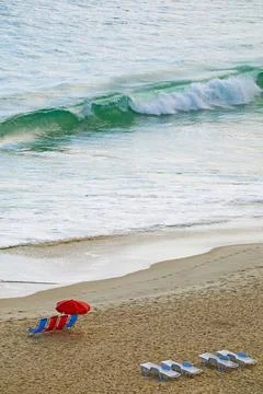 Empty beach with chairs and sunshade and the crashing waves in the sea Stockfoto's