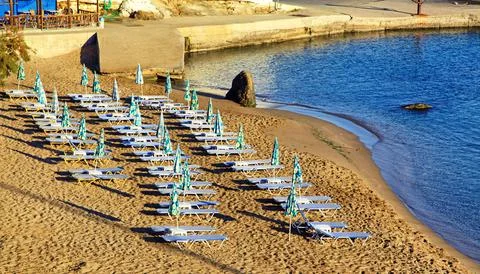 Empty beach chairs on sandy beach at reosrt Panormos in Crete island, Greece Stock Photos