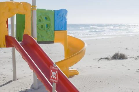 An empty beach, an empty playground, a sign with the inscription - translated Stock Photos