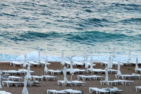 Empty beach, folded umbrellas on the background of a stormy sea Stock Photos