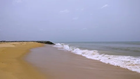 Empty beach with golden sands, waves crashing, cloudy skies shot in Chennai Stock Footage 94756100