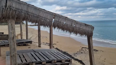 Empty beach huts overlooking calm sea under cloudy coastal sky Stock Footage 322124797