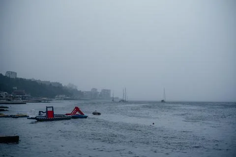 An empty beach with Inflatable floating water slide on a rainy day in the autumn Stock Photos