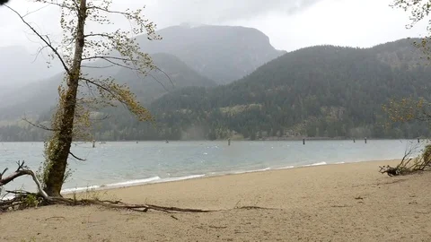 Empty beach on the lake shore. Bad weather. Rainy cloudy sky. Mountains. Stock-Footage 74866630