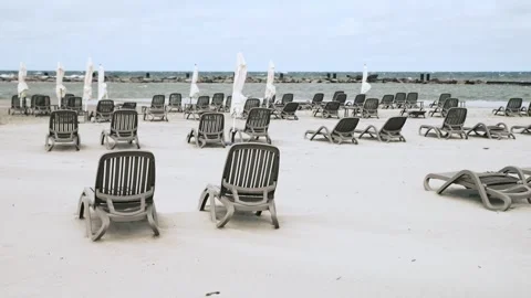 Empty beach loungers arranged evenly on pale sand near calm ocean under clo.. Stock Footage 337474749