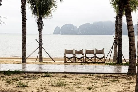 Empty beach, misty rain sky, palm trees, bungalows. Stock Photos