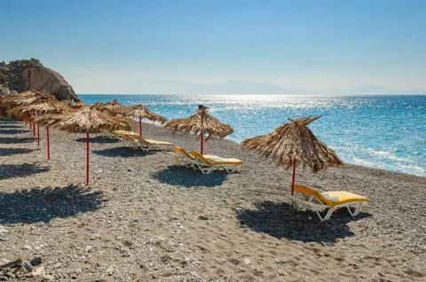 Empty beach with palm leaf umbrellas and lounge chairs on Greek island of Kos Foto stock