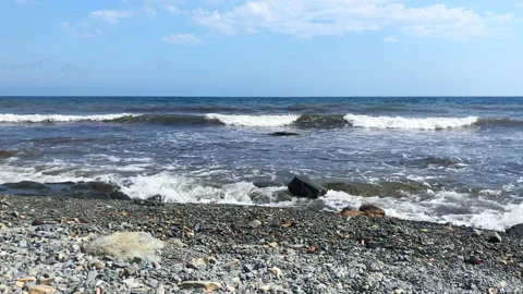 An empty beach on the sea, waves fall on a rocky shore against a background of Stock Footage 172244942