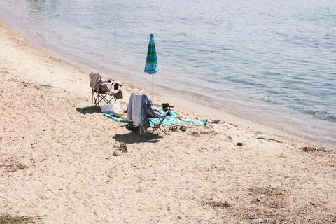 Empty beach set up with folding chairs and colorful umbrella on sandy shore Stock Photos
