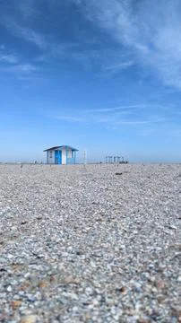 Empty beach with a single blue sea house under clear blue sky Stock Photos