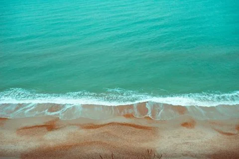 Empty Beach Split by Frothy Sea Waves on Windy Day Stock Photos