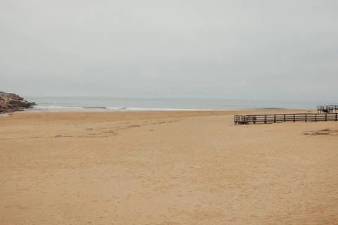 Empty beach stretches under soft, hazy sky Fotos Stock