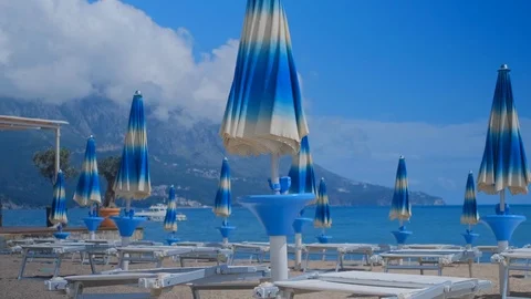 Empty beach with sunbeds and closed sunny umbrellas in Montenegro Stock Footage 127077904
