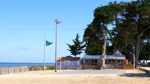Empty beach in a sunny day of summer. Green flag fluttering in slow motion. Stock Footage 120472399