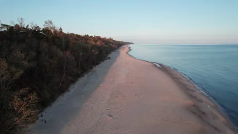 Empty beach at sunset, drone flight over the water reflecting the orange colo Stock Footage 210521978