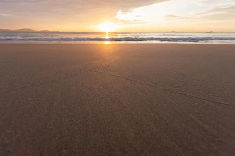 Empty beach at sunset with wet sand and subtle lines leading to the glowing.. Stock Photos