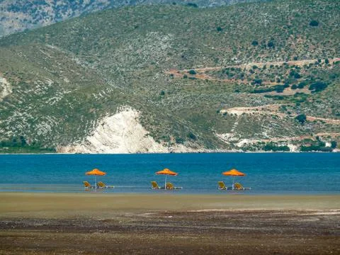 Empty beach with three umbrella and sunbeds in the sea Stock Photos