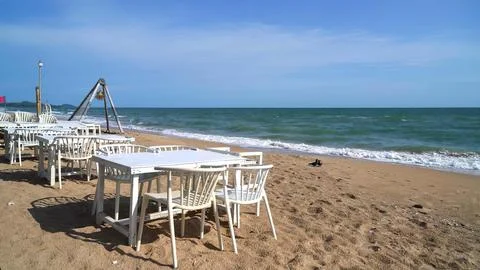 Empty beach with white tables and chairs near the sea Stock Photos