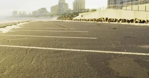 Empty beachside parking area with buildings in the background during sunset Ilustración de archivo