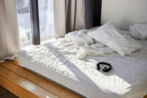 Empty bed in bedroom with headphones on it Stock Photos