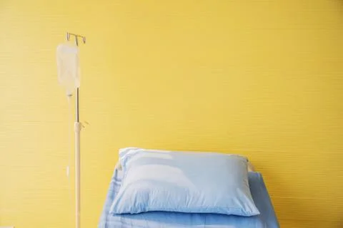 Empty bed with pillow and blanket and intravenous (IV) stand Stock Photos