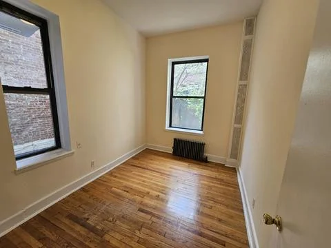 Empty bedroom with two windows, hardwood floor, and radiator Stock Photos
