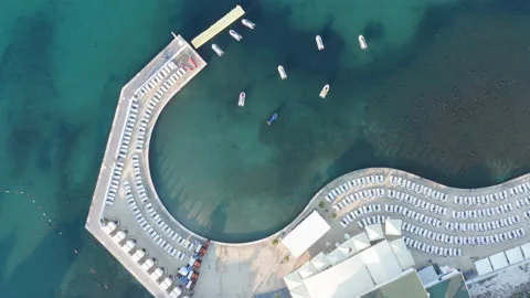 Empty beds on the concrete beach - pier or dock by shallow green sea water Stock Footage 213859719