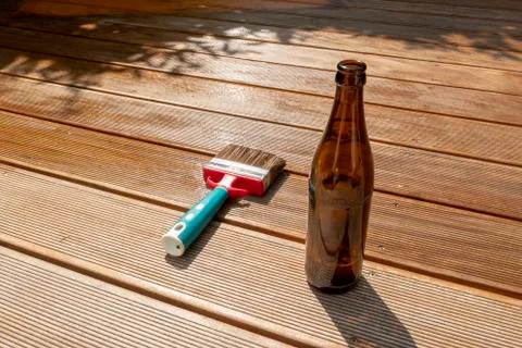 Empty beer bottle and a brush are lying on the half recessed terrace with gla Foto stock