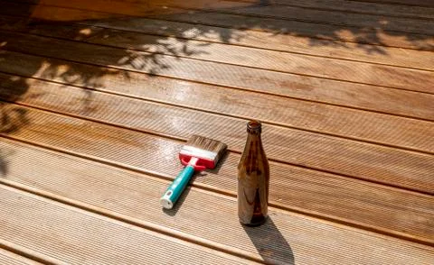Empty beer bottle and a brush are lying on the half recessed terrace with gla Stock Photos
