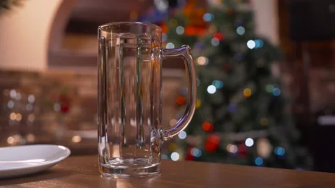 An empty beer mug stands on the table against the background of a Christmas tree Stock Footage 188516889