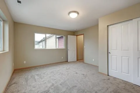 Empty beige bedroom interior of new contemporary home features wall to wall c Stock Photos
