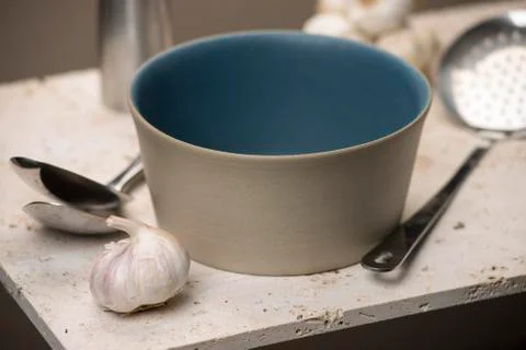 Empty Beige Flat Bottom Soup Bowl with Spoons and Garlic Stock Photos