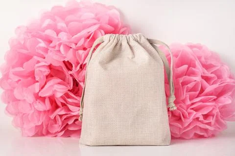 Empty beige gift bag on pink paper flowers background Stock Photos