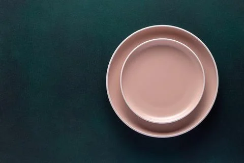 Empty beige plates on a dark green table, grunge background. Top view. Card.. Stock Photos