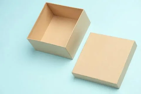 Empty beige square box with lid on blue background Stock Photos