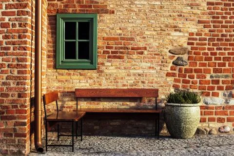Empty bench in brick wall corner with small window. Vintage styles photograph Stock Photos
