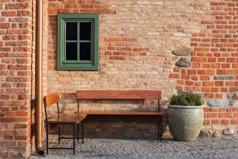 Empty bench in brick wall corner with small window. Vintage styles photograph Stock Photos