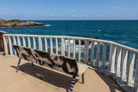 Empty bench on coastal promenade overlooking blue Atlantic Ocean in Asturias Stock Photos