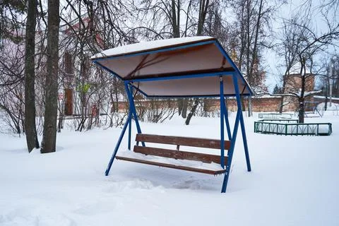 An empty bench covered in snow in a winter park Stock Photos