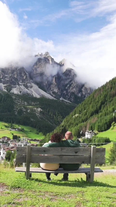 Empty bench facing village and snow-capped mountains in Dolomites, Italy Stockbeeldmateriaal 318950124