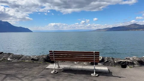 Empty bench by Lake Geneva with calm water and mountain view Switzerland 動画素材 331974775