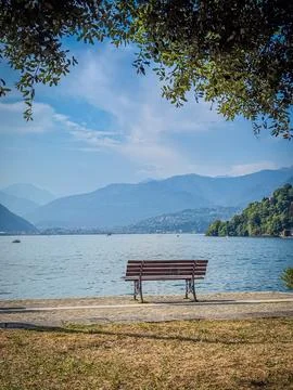 Empty bench by Lake Maggiore with mountain view on a summer day Fotos de archivo