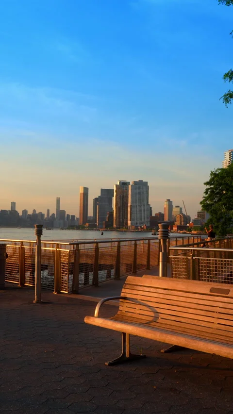 Empty bench lit by the setting sun at the quay of the East River. Manhattan Stock Footage 338308895